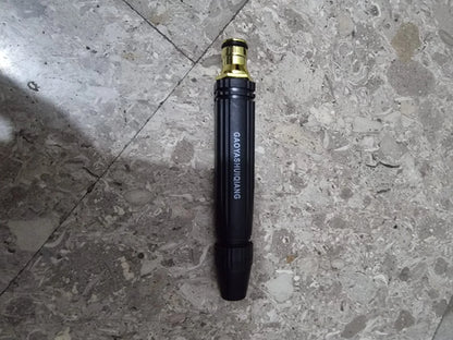 Heavy-duty metal spray nozzle attachment for a cordless pressure washer placed on a tiled floor. Durable black and brass design with adjustable spray settings for car washing, driveway cleaning, patio maintenance, and garden watering applications.
