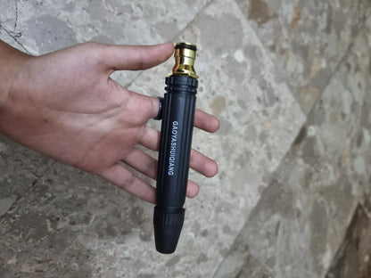 Hand holding a premium metal adjustable spray nozzle attachment for a cordless pressure washer. Durable black and brass construction designed for high-pressure cleaning, car washing, patio cleaning, and garden watering with adjustable spray patterns.